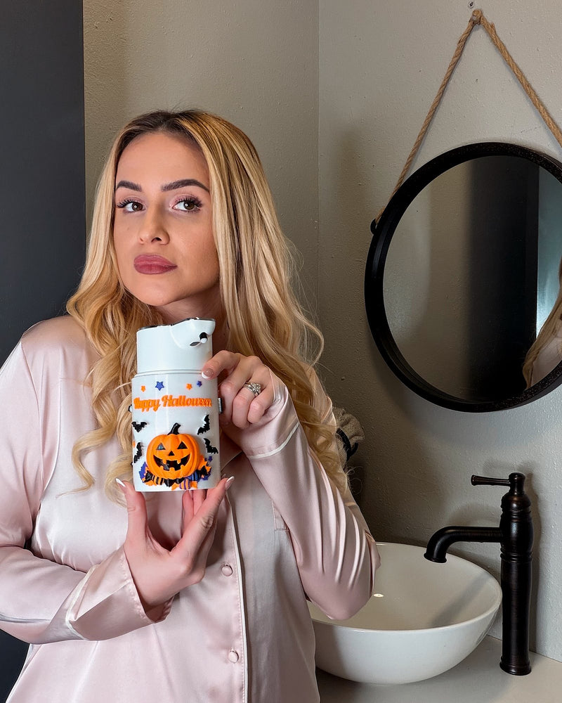 Happy Halloween automatic soap dispenser with 3D jack-o'-lantern held in a home bathroom